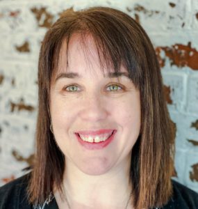 headshot of a smiling women with dark long hair and bangs