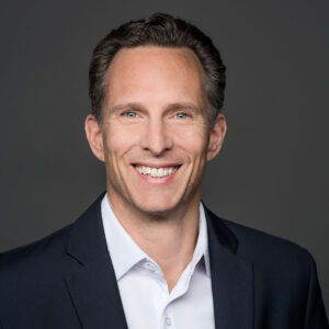 head shot of smiling man wearing a suit coat