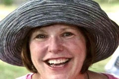 headshot of a women with a big smile and big blue fluffy hat