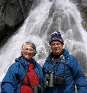 Picture of a smiling man and woman in front of waterfall