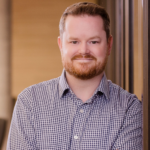 Headshot of smiling man with short hair and beard