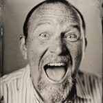 Black and white headshot of man with his mouth open